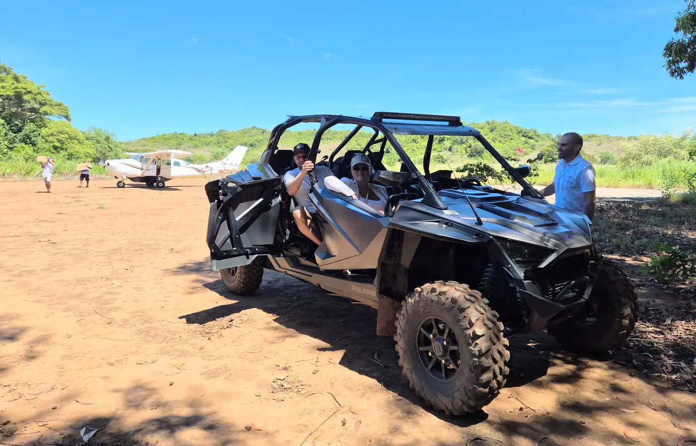 Off-road buggy and a small charter plane on a dirt airstrip in Madagascar