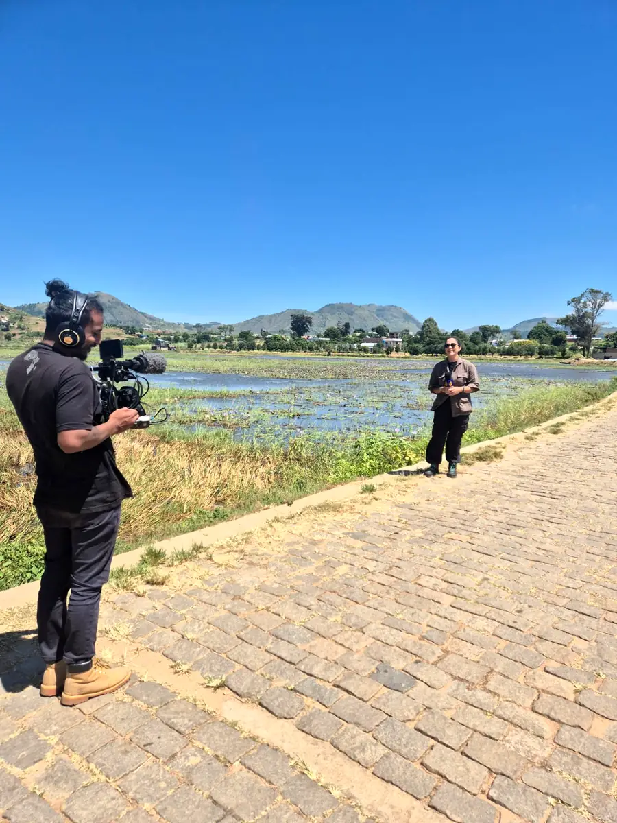 Camera operator filming a news reporter by a lake in the highlands of Madagascar