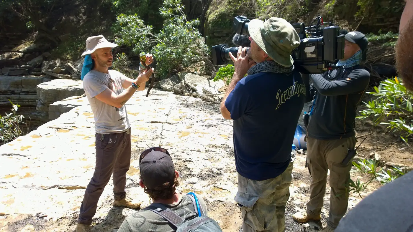 TV crew filming a presenter holding a chameleon in a canyon in Madagascar